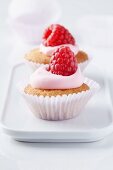 Mini muffins topped with raspberry mousse and fresh raspberries