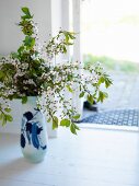 Vase mit Blumenzweigen auf Boden