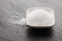 Fleur de sel in a bowl and on a slate surface