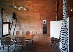 Essplatz mit Rattanstühlen im holzverkleideten Wohnraum im Designerstil