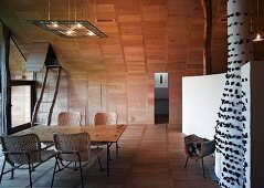 Dining area with rattan chairs in wood-panelled, designer room