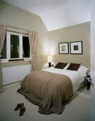 Modern bedroom in muted, natural colours with black-framed pictured above French bed