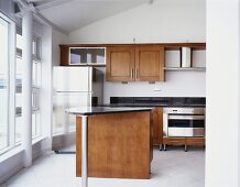 Theke mit schwarzer Granitplatte und Edelstahl-Kühlschrank in moderner Einbauküche mit Holzfronten