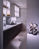 Pair of sculptures with Mongolian features on pedestal in contemporary kitchen with designer appliances