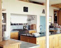 Moderne Landhausküche mit Holzfronten und schwarzer Steinplatte auf dem Spülenblock