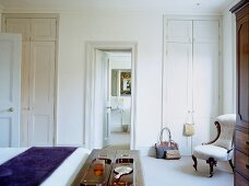 Traditionelles Schlafzimmer in Weiß mit raumhohen Einbauschränken und gepolstertem, romantischem Stuhl