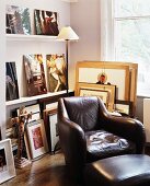 Comfortable leather armchair with matching footstool in front of shelves with collection of pictures
