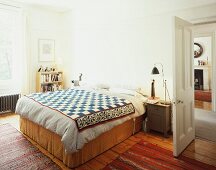 Double bed with ethnic bedspread next to open door in bedroom