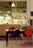 Colourful Bauhaus chairs in dining area in front of half open kitchen cupboard