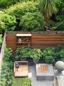 Blick auf eingezäunte Terrasse mit Holzbank vor gefliestem Podest und Boden