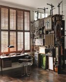 Vintage style desk below window with closed shutters next to shelves with collectors' items