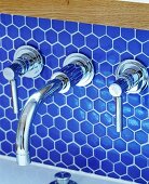 Chrome, designer, wall-mounted tap fitting on blue mosaic wall tiles