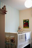 Cot made of white-painted slats against wall with striped wallpaper
