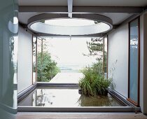 Loggia in zeitgenössischer Architektur mit Pflanzentöpfen im Wasserbassin vor Garten