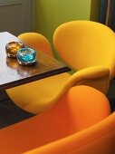 Small table in a bar with bright orange and yellow, retro-style shell chairs