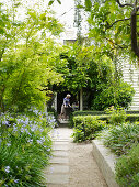 Weg zwischen angelegtem Garten vor Haus mit Terrassenplatz