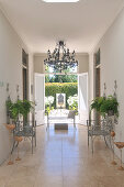 Metal chairs on marble floor in foyer of country house with open terrace doors