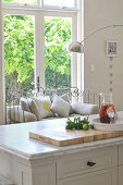 Kitchen island with marble top and metal-framed bench in front of terrace door