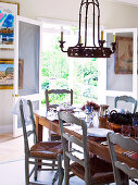 Chandelier hanging above set table in front of open door with view of garden