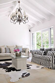 Couch with black and white striped cover and animal-skin rug on floor of simple, renovated country house