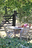 Wooden table and chairs in garden in front of closed gate