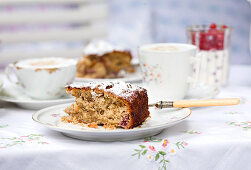 A piece of cake with an antique fork on an old floral china tea set with a matching tablecloth