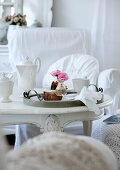 Breakfast crockery and small vase of roses on vintage tray on antique, white-painted table