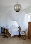 Platform bed with beautifully draped canopy in country house bedroom