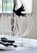 Black bird ornament on white-painted metal frame