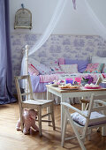Pastries on table and rustic children's chairs in front of canopied bed in child's bedroom