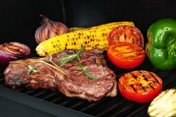 Steak, vegetables and corn on the cob on a grill