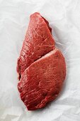 Raw beef steak on greaseproof paper