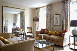 Light sofa set and delicate metal side table in front of large mirror in traditional living room