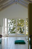 Open-plan attic room with floor cushion in front of balcony doors