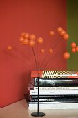 70s-style ornament with metal base and spray of spheres next to stack of books against red-painted wall