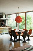Brown plastic shell chairs with orange cushions in dining area below orange pendant lamp