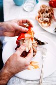 Man removing the meat from a lobster claw