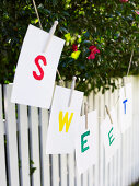 Pieces of paper spelling the word SWEET hanging on a washing line