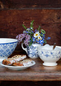 Posy of herbs in mug, sugar bowl and slices of cake