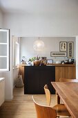 Wood with dark accents - view from dining area of cosy kitchen with island below spherical, retro glass light fitting