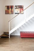 Couch covered with pink leather in niche below modern staircase