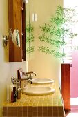 Vanity with yellow tiles and round basin and delicate branch in a modern floor vase