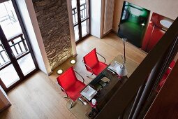 View down into dining area with rustic stone wall, antique table with glass top and modern swivel chairs