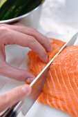 A salmon fillet being cut into portions