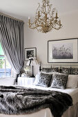 White, country house bedroom with grey accessories and gilt chandelier