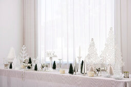 Christmas decorations on long table below window with closed curtain
