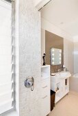 Small, polygonal tiles on wall with shower fittings in modern bathroom
