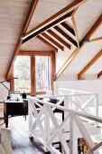 Workspace under sloping ceiling on gallery with white wooden balustrade