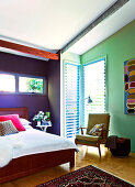 A double bed in a colourful bedroom under a sloping roof