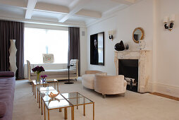 Elegant period living room with small brass and glass tables and unusual upholstered seating